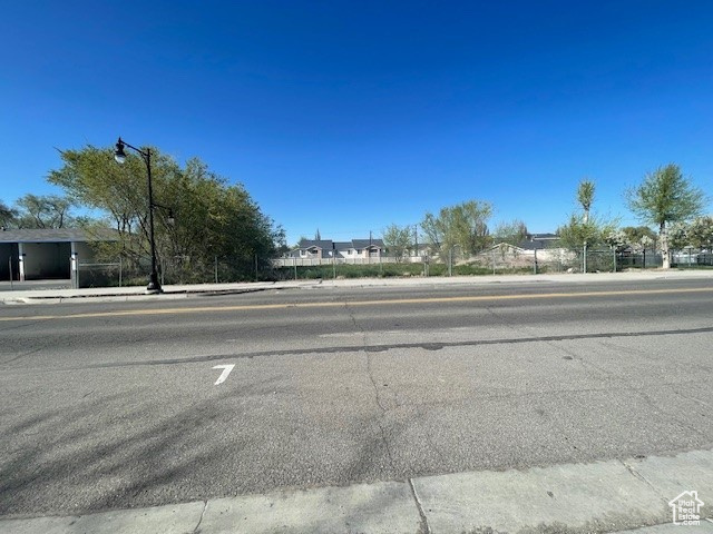 View of asphalt road with sidewalks, street lighting, and curbs