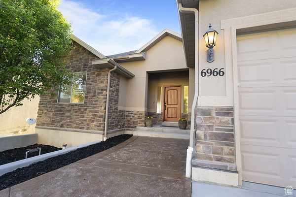 Doorway to property featuring stone siding, stucco siding, and a garage