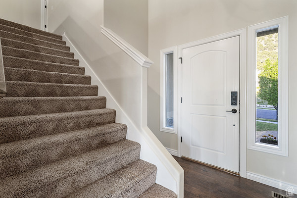 Foyer with stairs, dark wood-type flooring, and baseboards