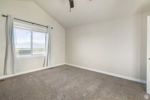 Unfurnished room featuring lofted ceiling, a ceiling fan, carpet floors, and baseboards