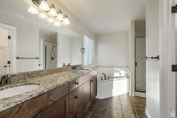 Bathroom with a shower stall, a bath, double vanity, and stone finish floors