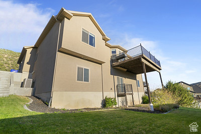 Rear view of house with a balcony, stucco siding, and a yard
