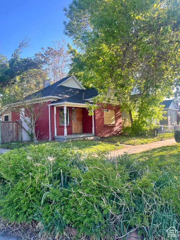 View of front of house with fence, brick siding, a chimney, and a shingled roof