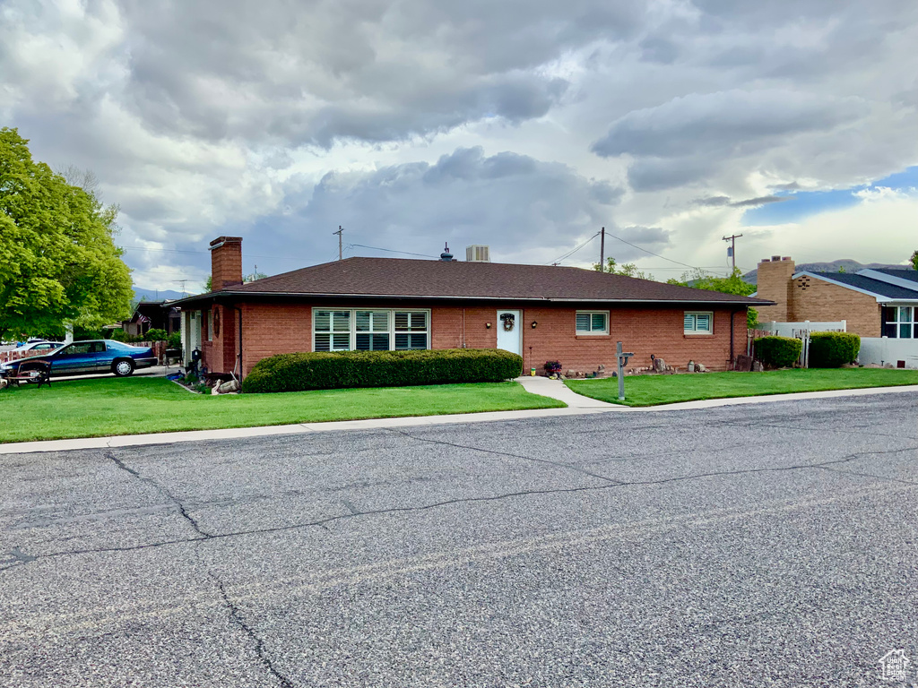 Single story home with a chimney, brick siding, and a front lawn