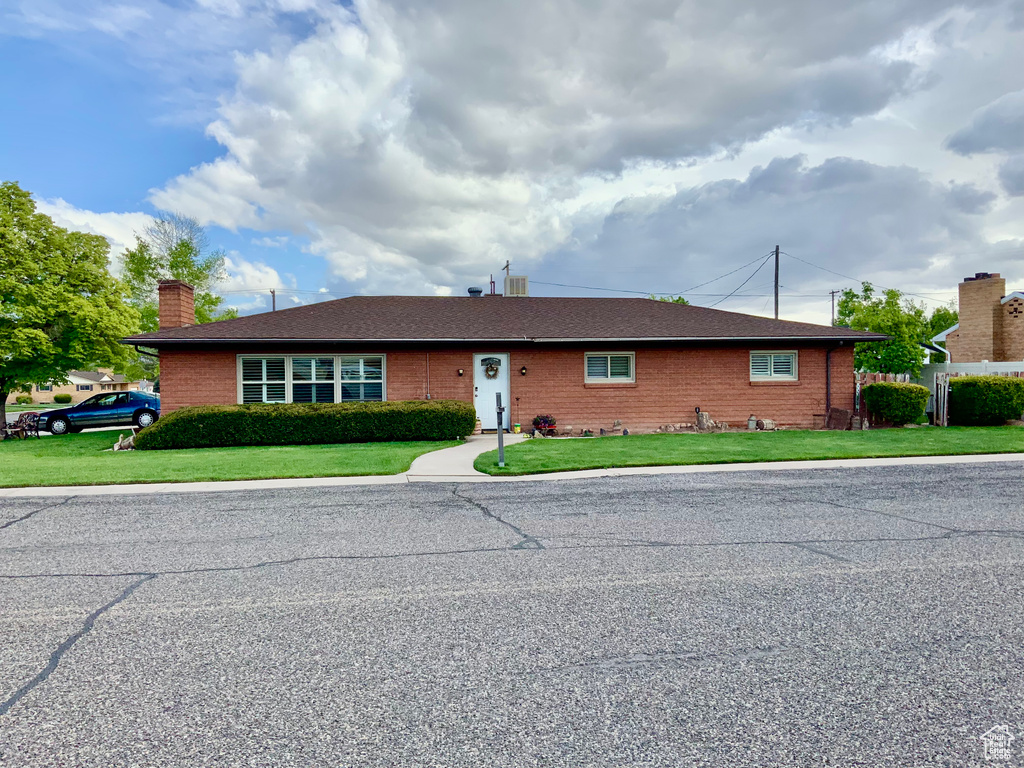 Single story home featuring a chimney, a front lawn, and brick siding