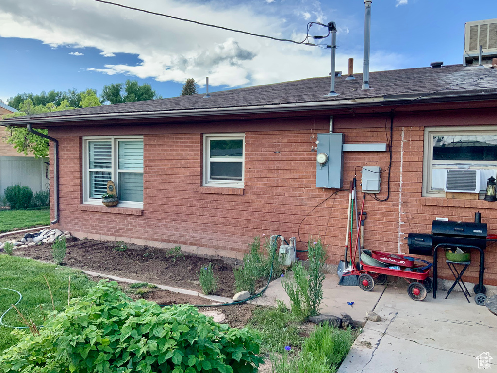 View of side of property with brick siding, a shingled roof, central AC, and cooling unit