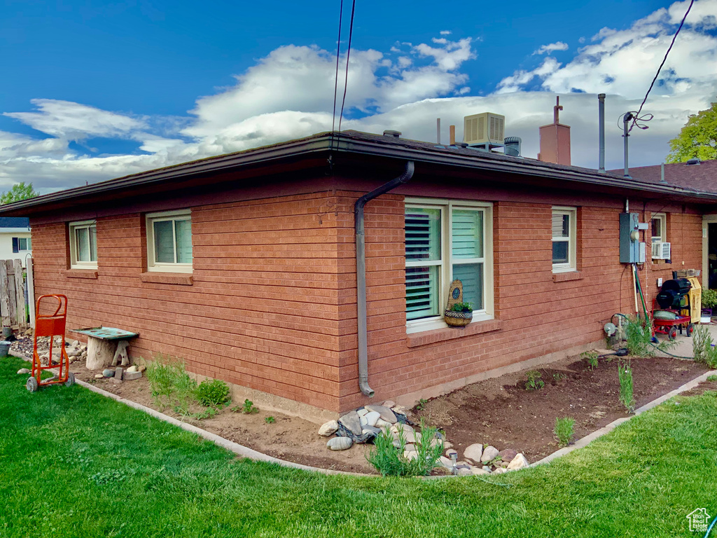 View of home\\\'s exterior with a lawn, a chimney, central air condition unit, and brick siding