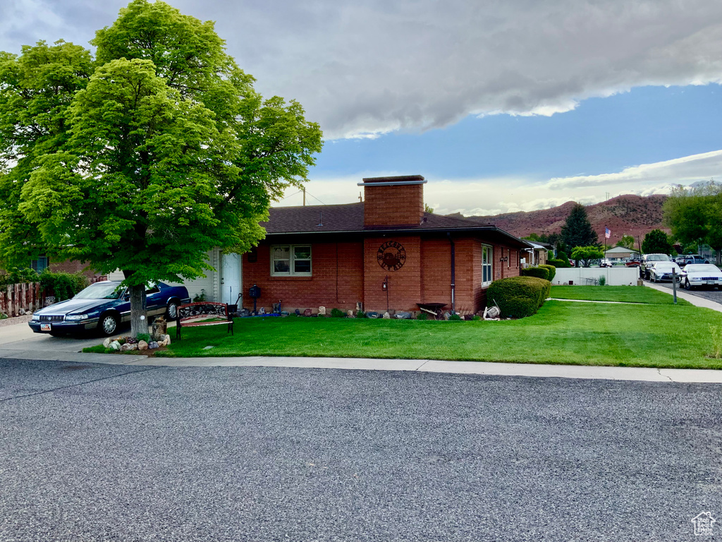 View of front facade featuring a chimney, brick siding, a mountain view, a shingled roof, and driveway