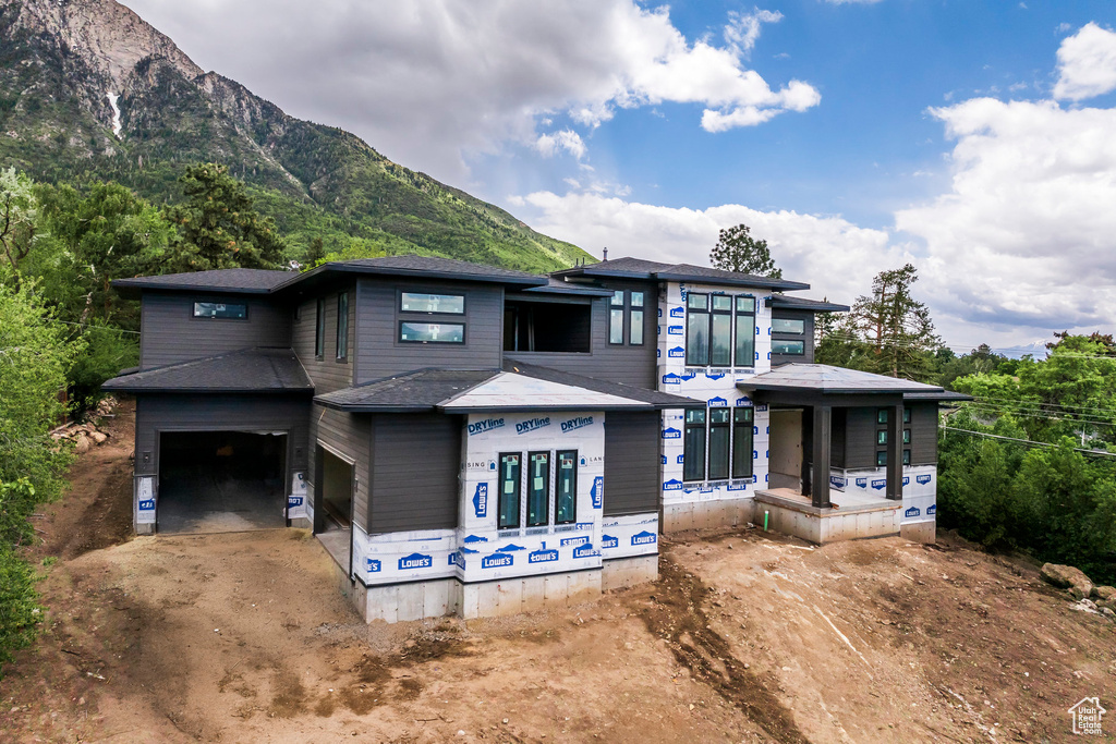 View of front of property featuring dirt driveway, a mountain view, and an attached garage