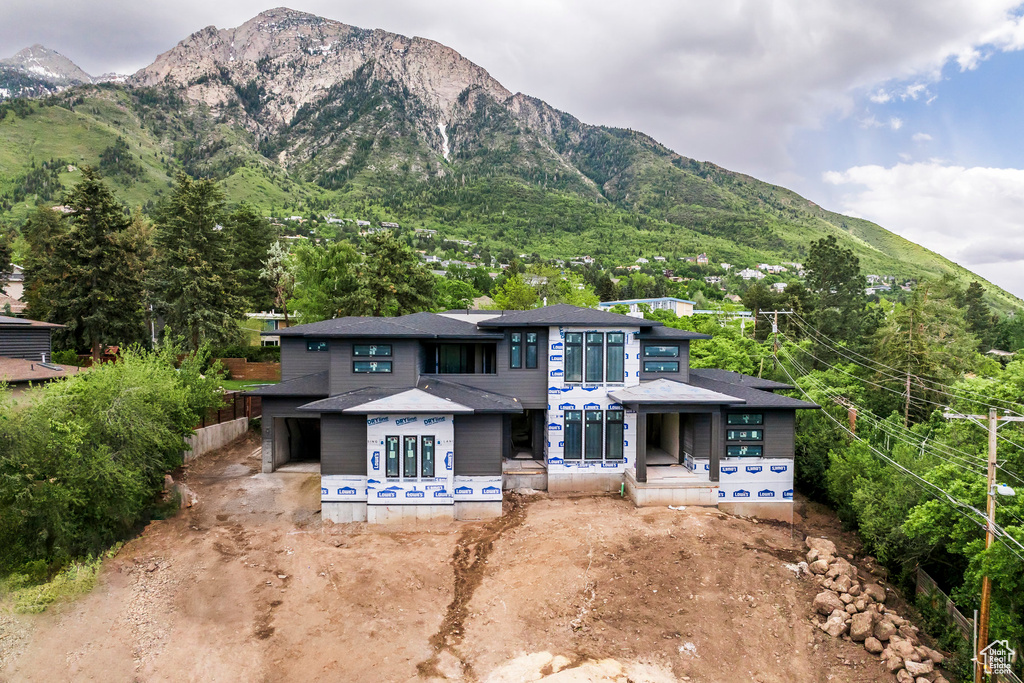 View of front of house with a mountain view, a shingled roof, and driveway