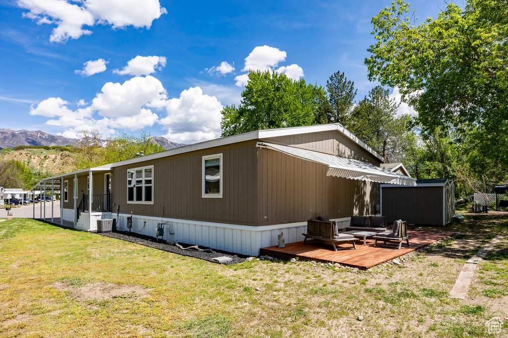View of side of property featuring a deck with mountain view, a yard, and central air condition unit