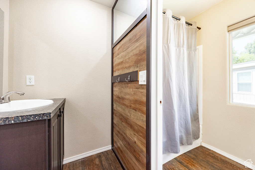 Full bathroom featuring wood finished floors, vanity, baseboards, and shower / bathtub combination with curtain