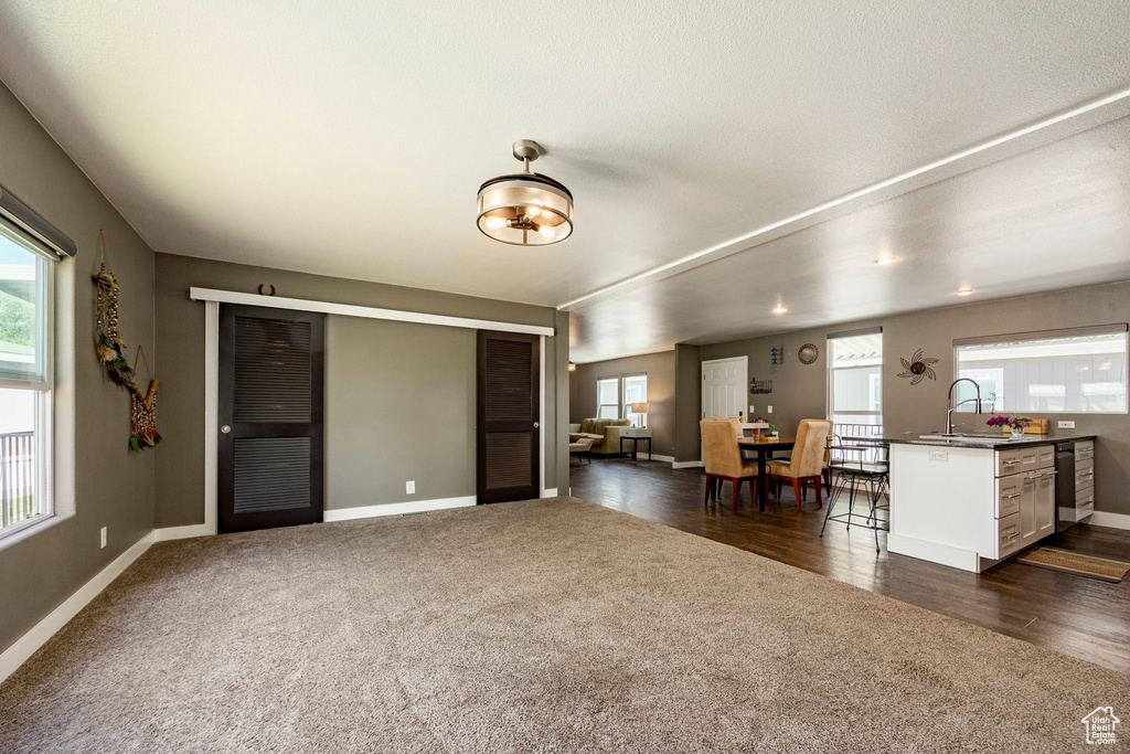Living area with dark carpet, baseboards, and dark wood-style flooring