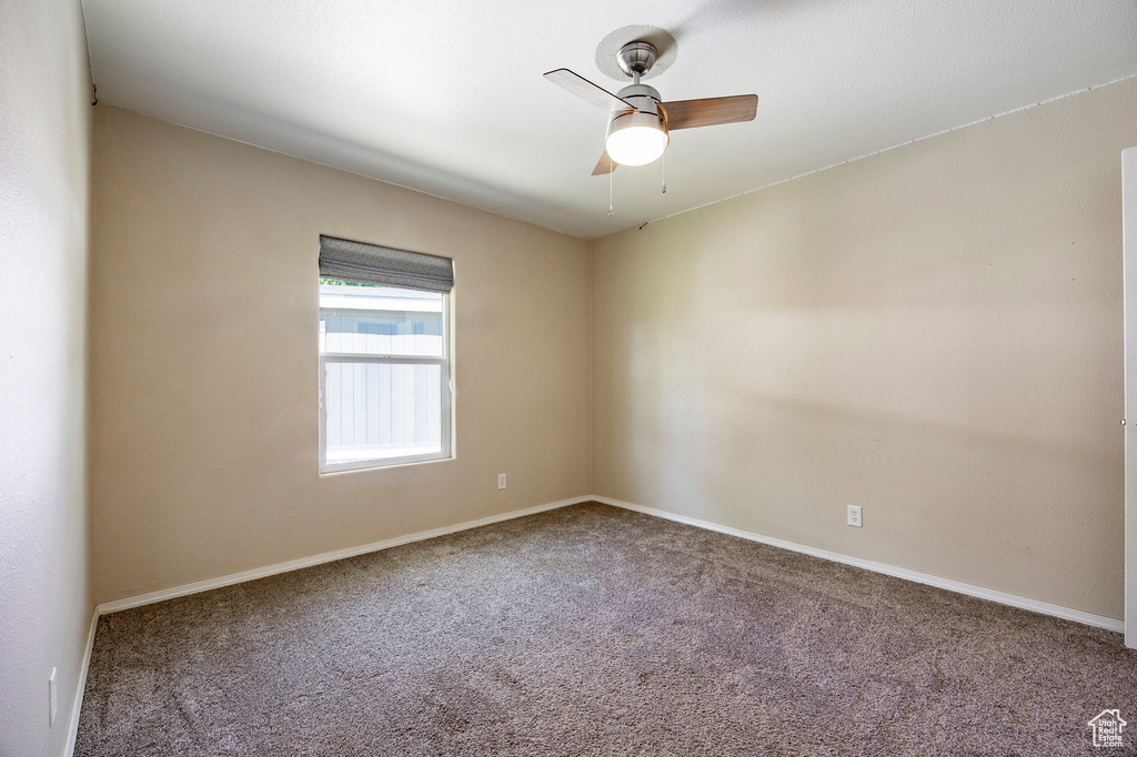 Carpeted empty room with a ceiling fan and baseboards