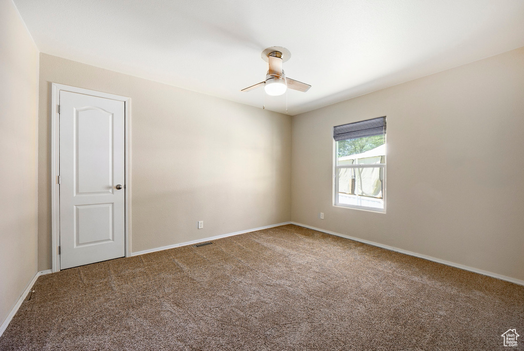 Spare room featuring a ceiling fan, carpet, and baseboards