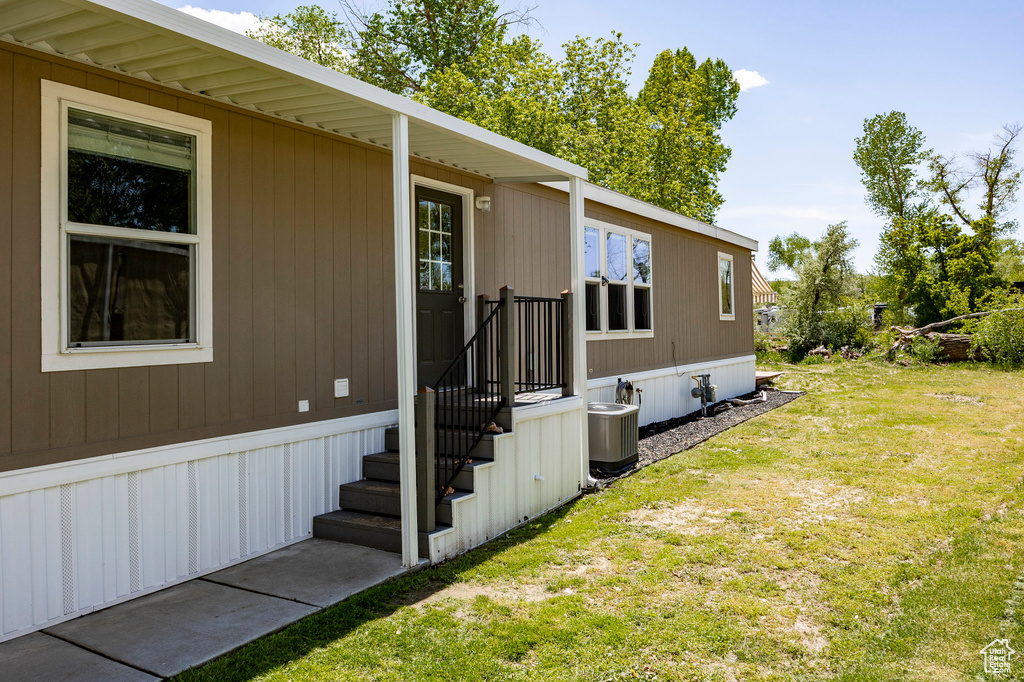 View of side of home with a yard and cooling unit