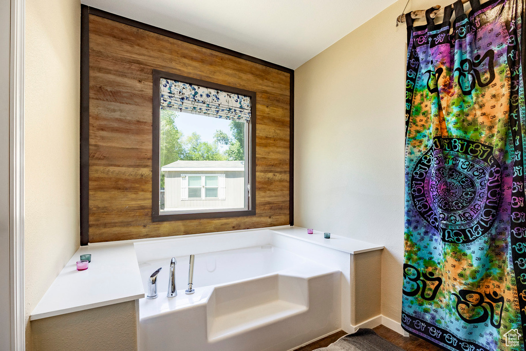 Full bath featuring a garden tub and wood walls