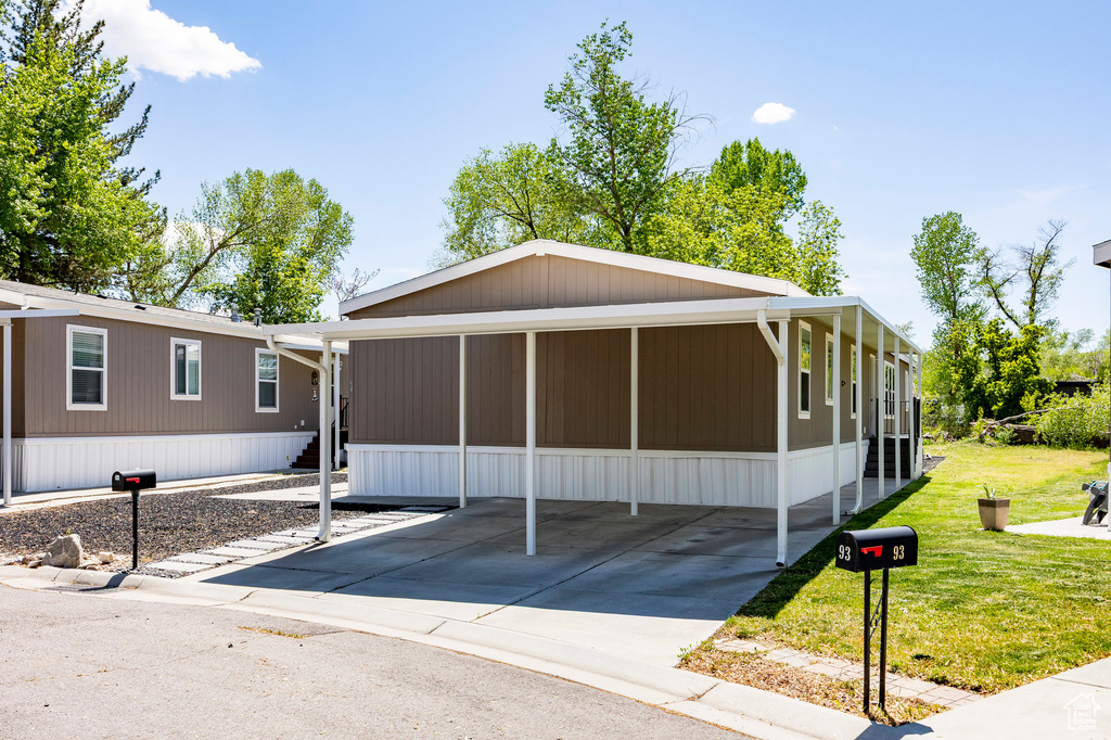 Manufactured / mobile home featuring a front lawn, a sunroom, and driveway