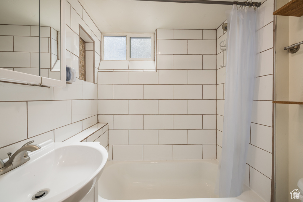 Full bath with a sink, shower / tub combo with curtain, tile walls, and tasteful backsplash