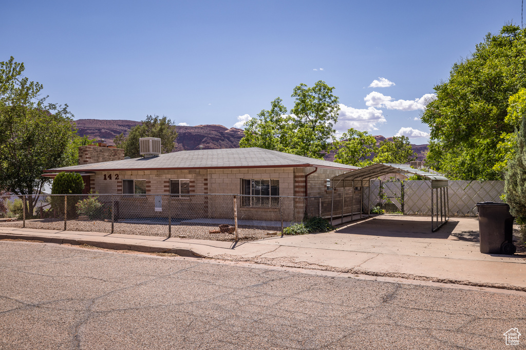View of front facade featuring a carport, fence, concrete driveway, and a mountain view