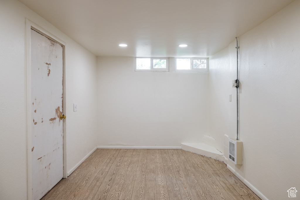 Basement featuring light wood-style floors, recessed lighting, heating unit, and baseboards