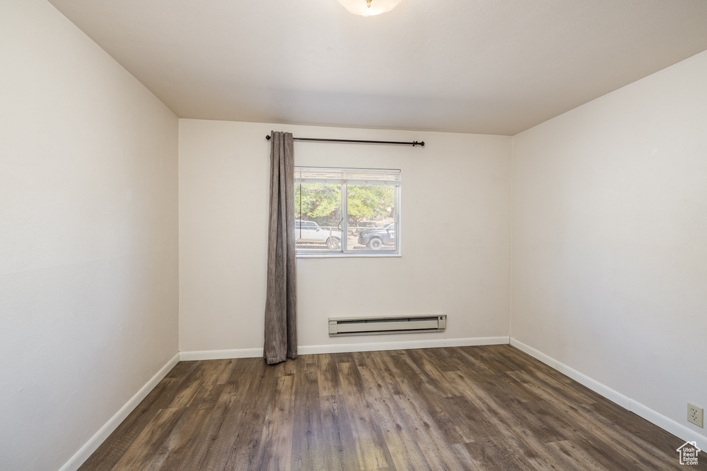Spare room featuring baseboard heating, wood finished floors, and baseboards