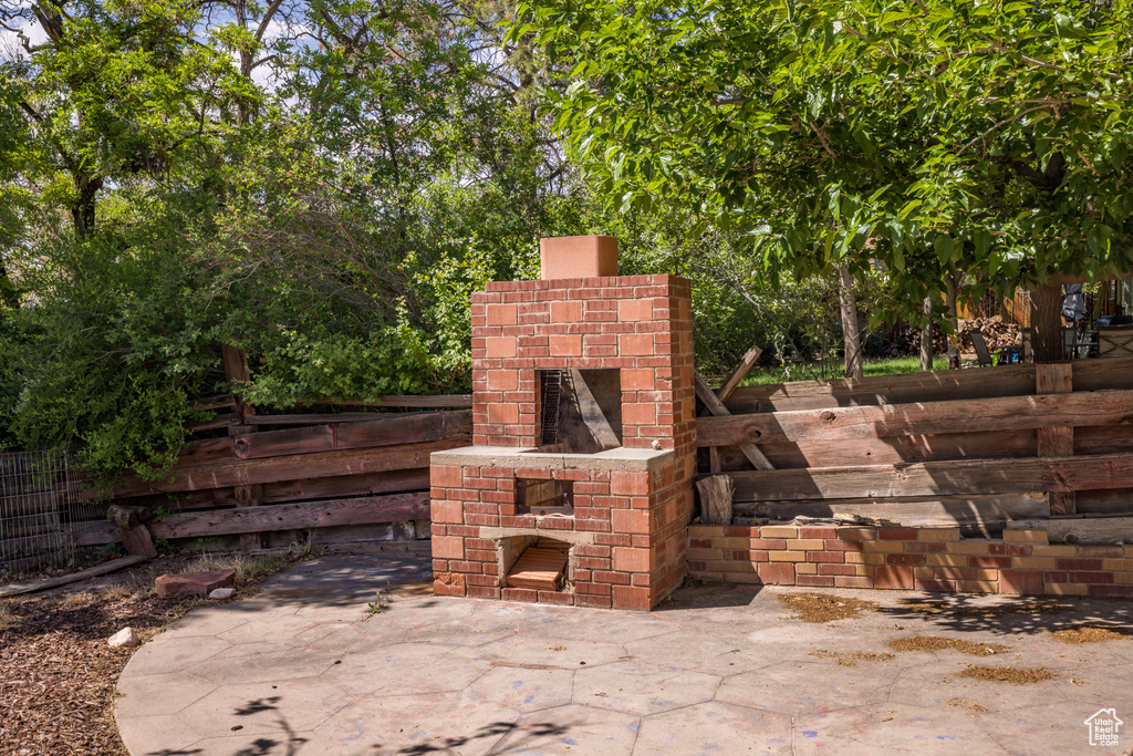 View of patio / terrace featuring an outdoor brick fireplace and fence