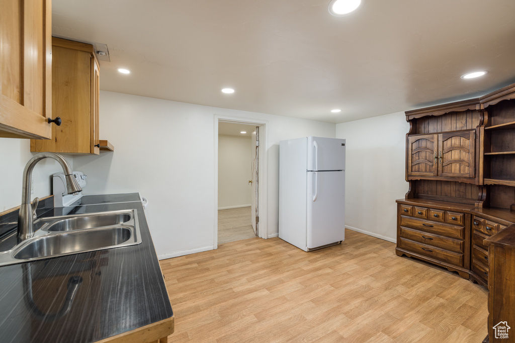 Kitchen with freestanding refrigerator, a sink, light wood-type flooring, recessed lighting, and baseboards