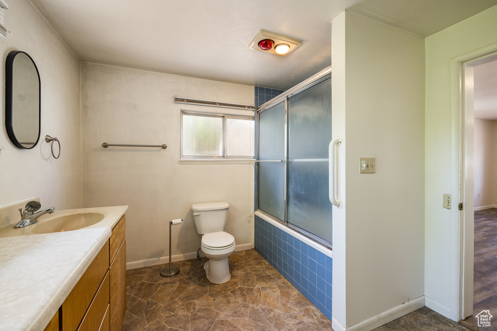 Full bathroom featuring toilet, enclosed tub / shower combo, vanity, and baseboards
