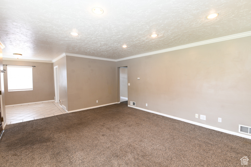 Carpeted spare room with baseboards, a textured ceiling, recessed lighting, ornamental molding, and tile patterned flooring