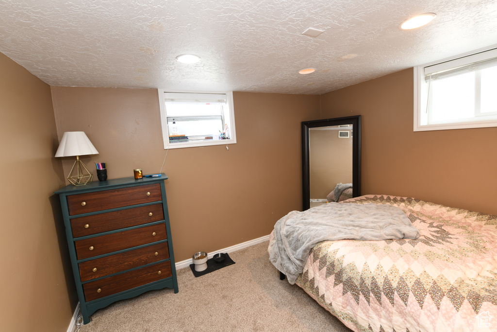 Bedroom featuring light carpet, multiple windows, a textured ceiling, baseboards, and recessed lighting