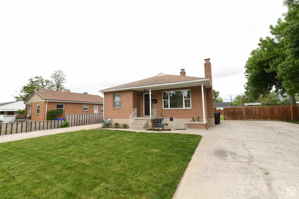 Bungalow with brick siding, driveway, and a chimney