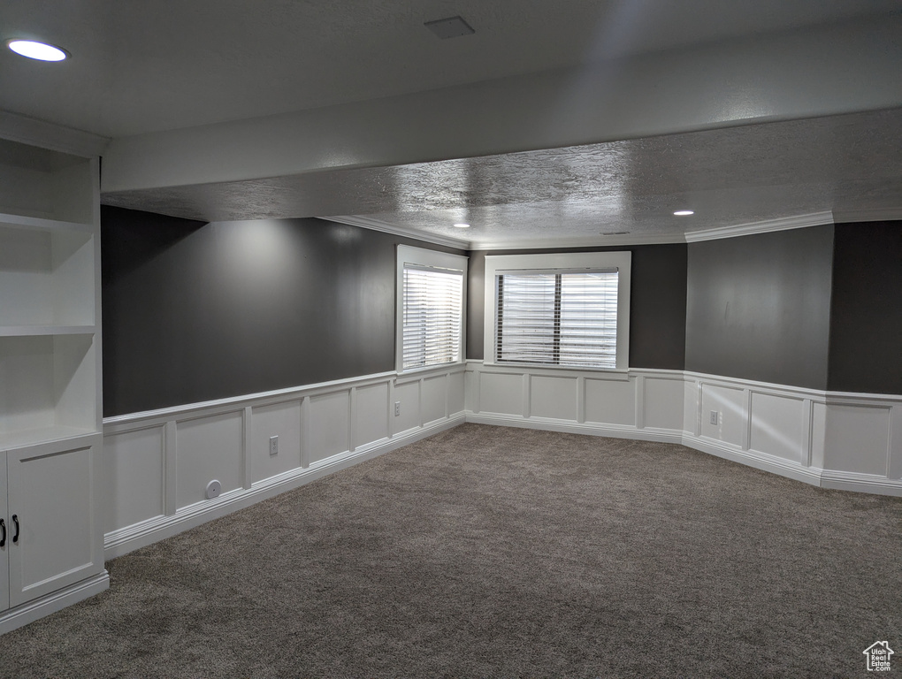 Spare room featuring crown molding, a decorative wall, carpet flooring, recessed lighting, and a wainscoted wall