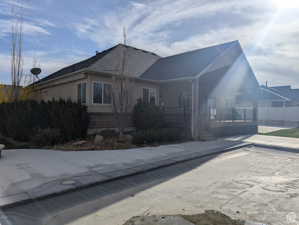 View of home's exterior featuring covered porch, brick siding, and a shingled roof
