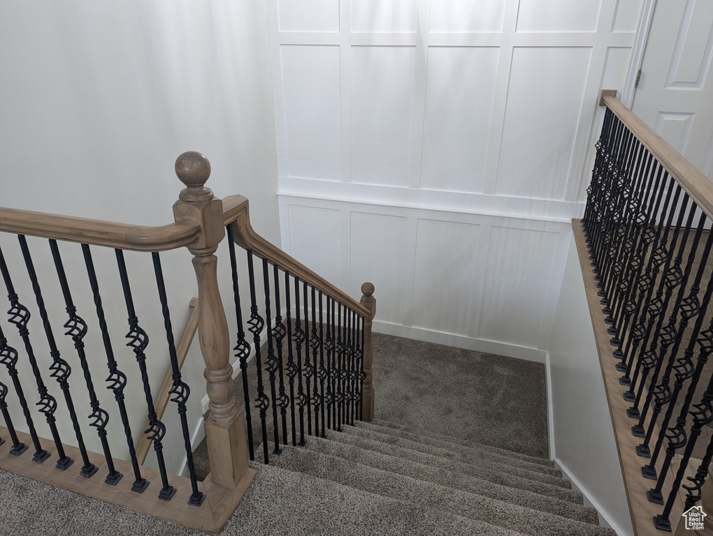 Stairs with a decorative wall and carpet flooring