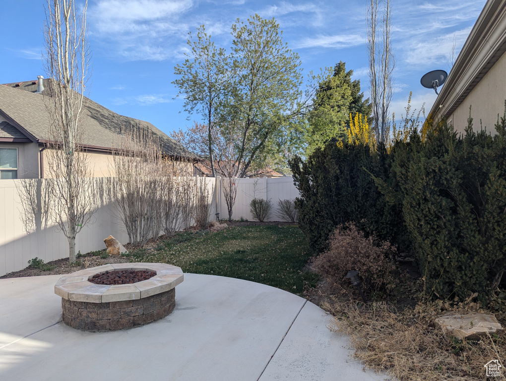 Fenced backyard featuring a patio area and a fire pit