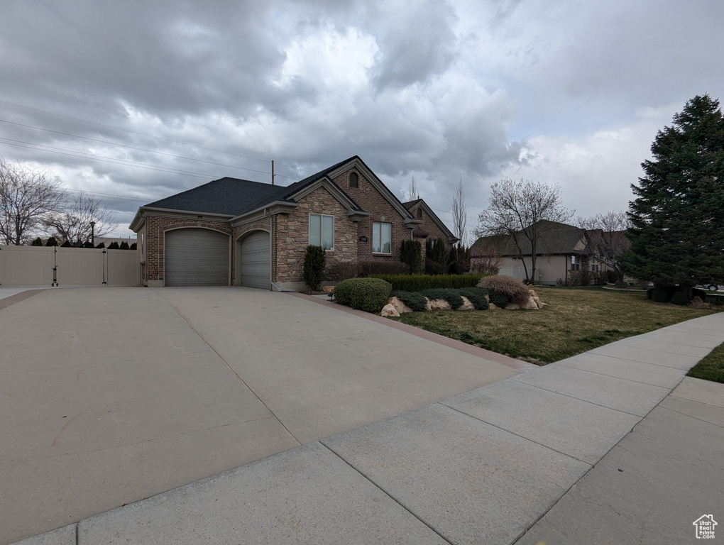 Single story home with a gate, a garage, driveway, brick siding, and roof with shingles