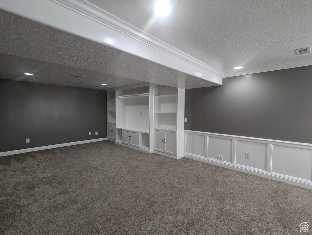 Finished below grade area with a textured ceiling, carpet flooring, crown molding, and recessed lighting