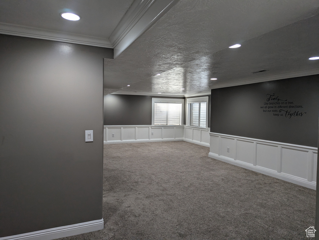 Spare room featuring ornamental molding, carpet, recessed lighting, a decorative wall, and wainscoting