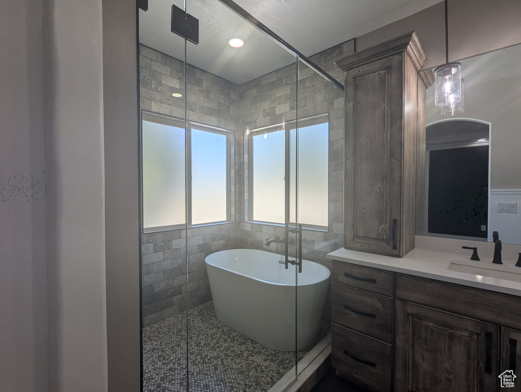 Full bath with a soaking tub, vanity, tile walls, and tile patterned floors