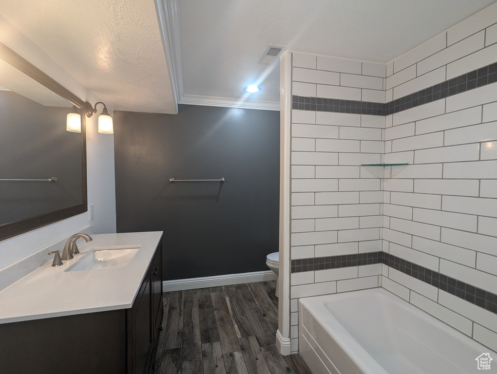 Bathroom with vanity, wood finished floors, ornamental molding, shower / bath combination, and a textured ceiling