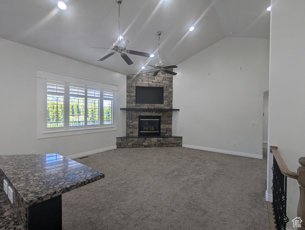 Unfurnished living room with carpet floors, a ceiling fan, vaulted ceiling, and a fireplace