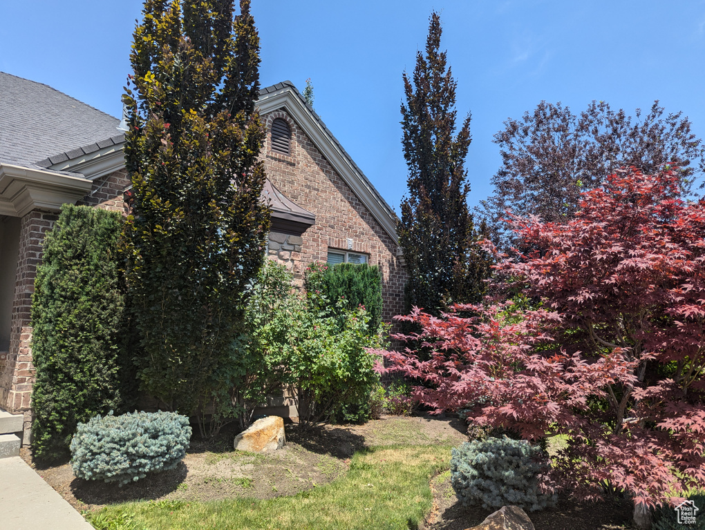 View of home\\\\\\\'s exterior featuring brick siding, stone siding, and roof with shingles
