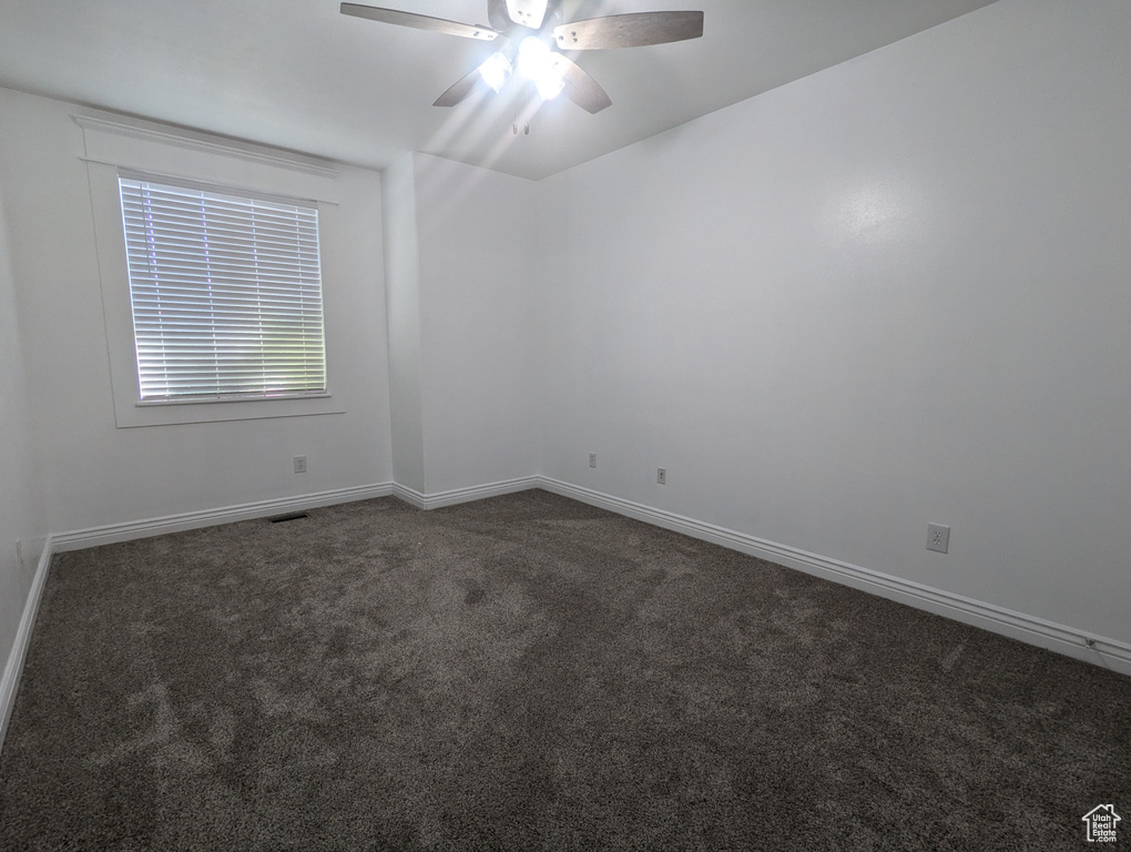 Spare room featuring dark carpet and a ceiling fan