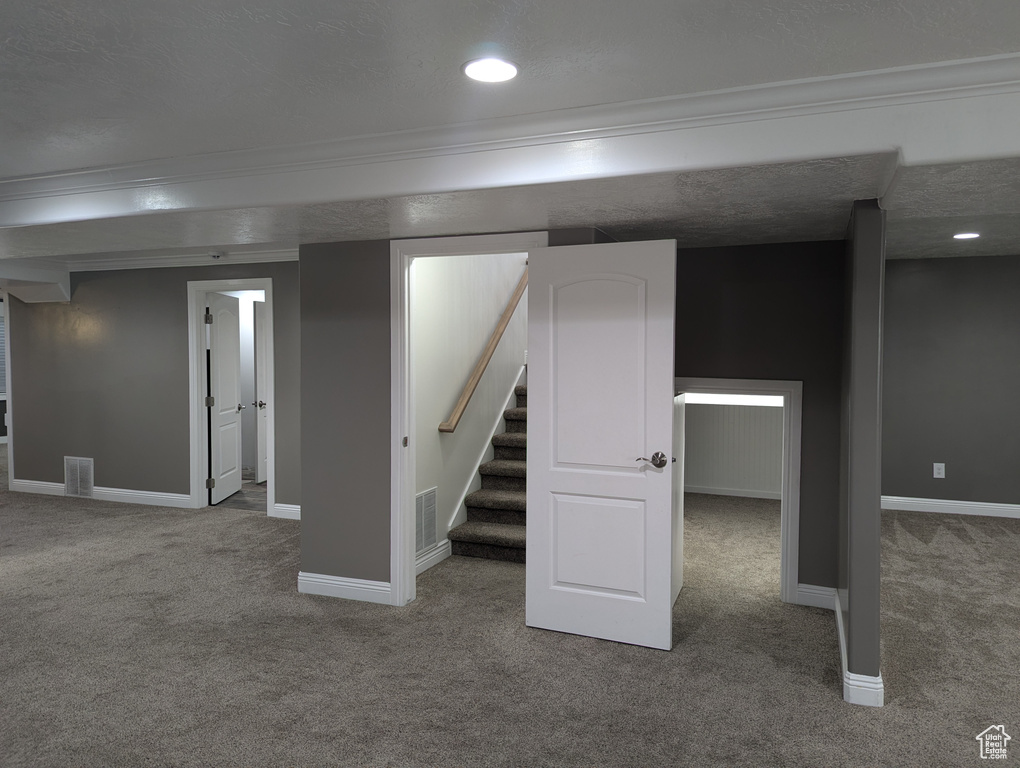 Finished below grade area featuring carpet floors, ornamental molding, baseboards, stairway, and recessed lighting