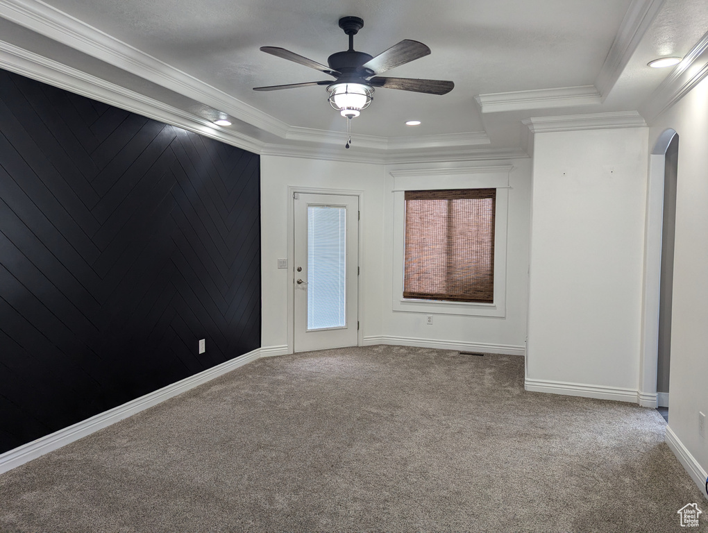 Spare room with arched walkways, carpet, ceiling fan, crown molding, and baseboards