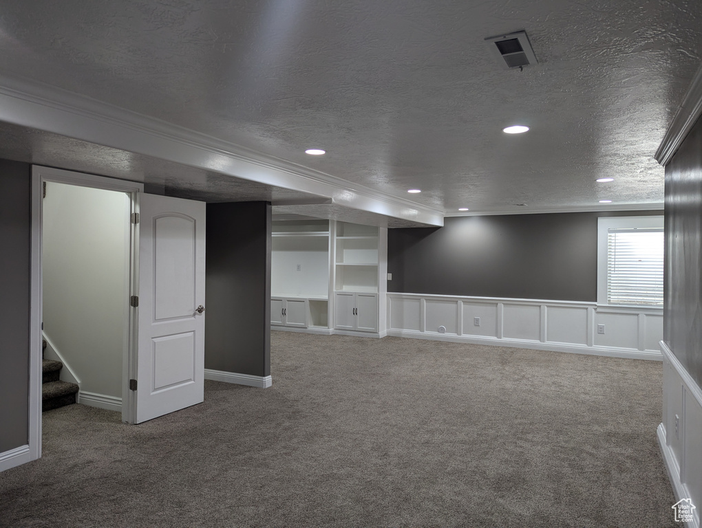 Below grade area with ornamental molding, carpet flooring, a textured ceiling, stairway, and recessed lighting