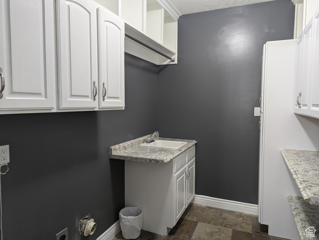 Laundry room featuring cabinet space and dark stone finish flooring