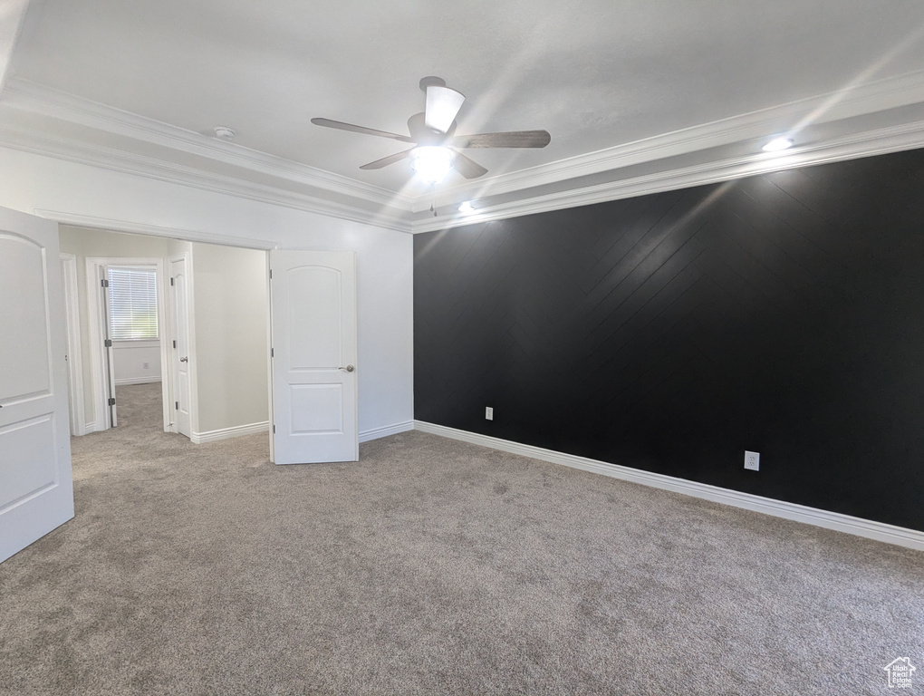 Unfurnished bedroom featuring light colored carpet, crown molding, and a ceiling fan