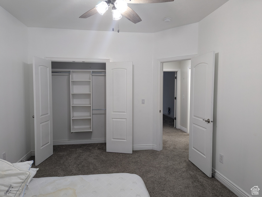 Unfurnished bedroom featuring dark carpet, a closet, baseboards, and ceiling fan